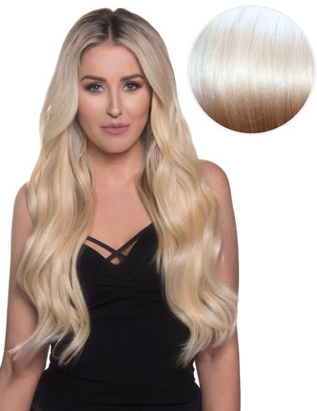 Eine Frau mit langen, blonden Haaren in einem schwarzen Top. Ein Farbmuster zeigt hellblonden Hautton.