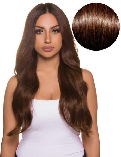 Eine Frau mit langen, gewellten braunen Haaren und weißem Oberteil, Nahaufnahme von Haarfarbe und Textur.