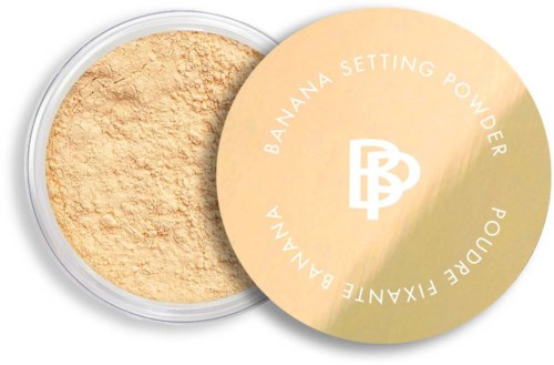 A round container of banana setting powder with a yellow lid. Some powder is visible inside.