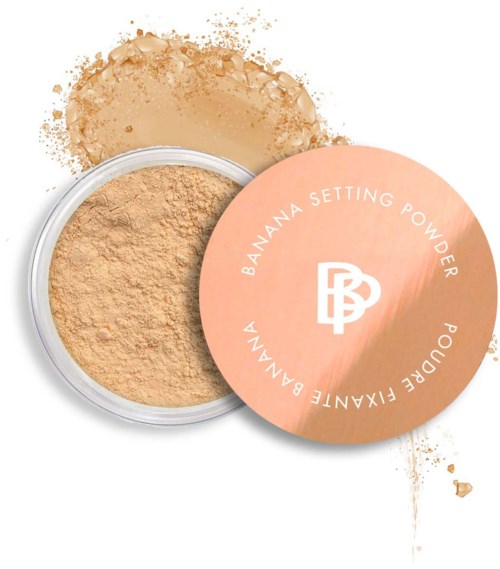 A compact container of banana setting powder with a pink lid, some loose powder around.
