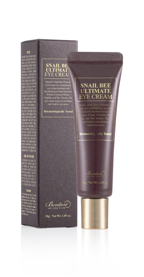 Een donkergekleurde tube en doos met label voor snail bee oogcrème, met gouden accenten, rechtopstaand.