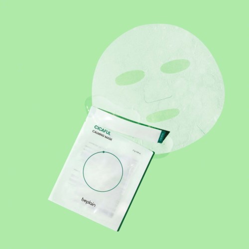 Een vel papier met een gezichtsmaske-ontwerp, naast een pakketje met 'CICAFUL CALMING MASK'.