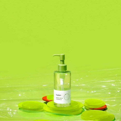 Handdesinfektionsflasche auf Wasseroberfläche mit grünen und orangenen schwebenden Objekten, Hintergrund hellgrün.