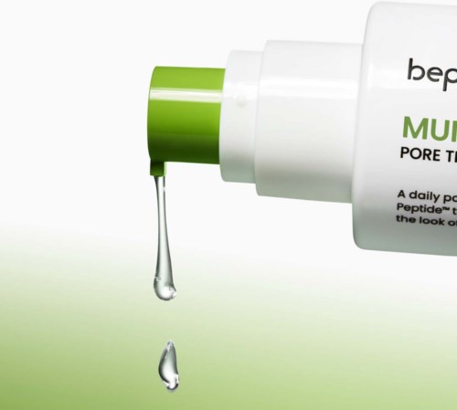 Een witte fles met groene dop die een heldere vloeistof vrijgeeft, gelabeld voor poriebehandeling.