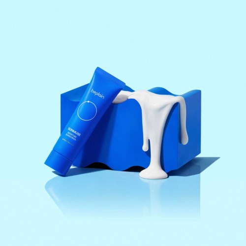 Een blauwe tube zonnebrandcrème met witte crème die over een blauwe doos stroomt tegen een lichtblauwe achtergrond.