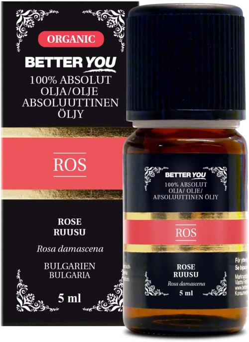 A small brown bottle of rose essential oil with black and red labels, and a matching box beside it.