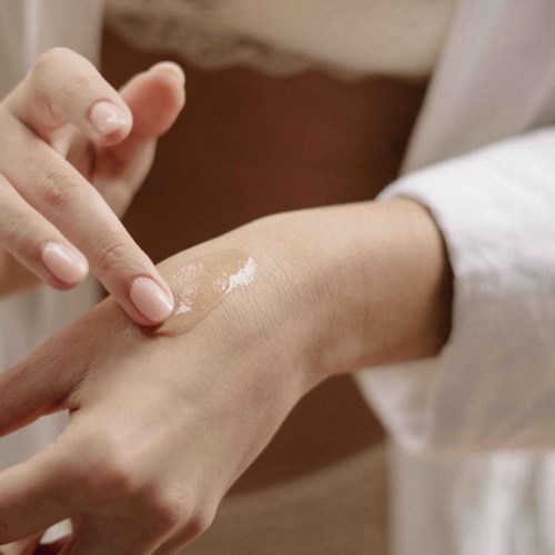 Eine Person trägt Lotion oder Creme mit einem Finger auf die Hand auf.