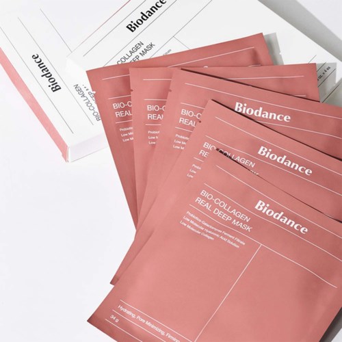 Mehrere rosa Bio-­Collagen-Masken sind auf weißem Papier ausgebreitet. Ein ähnliches Box liegt in der Nähe.