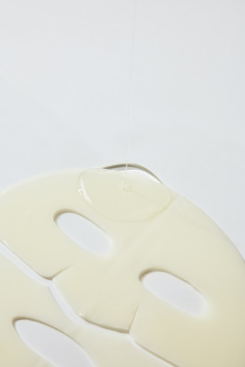A white sheet mask with eye and mouth holes on a light background.