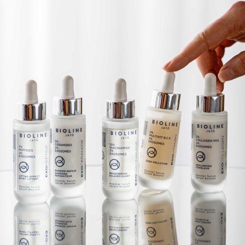 Five skincare bottles with dropper caps stand in a row, featuring different labels and ingredients.