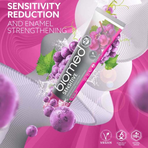 A tube of Biomed Sensitive toothpaste with grapes and water splash design, highlighting sensitivity and enamel strengthening.