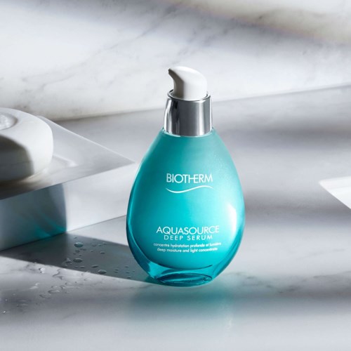 Een blauwe fles Biotherm Aquasource Deep Serum met doseerpomp op marmeren oppervlak.
