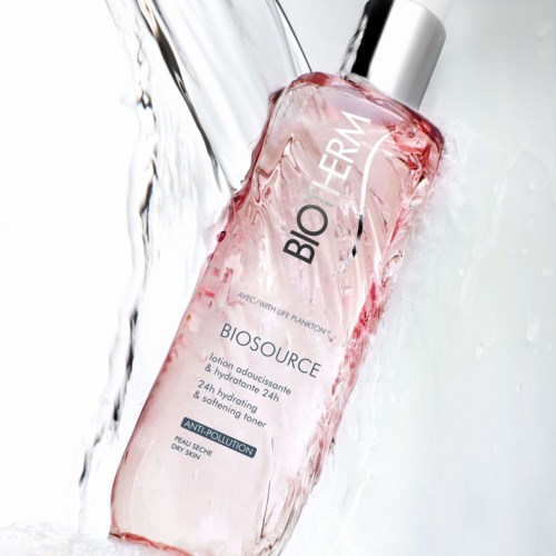Een roze fles met label 'BIOSOURCE' en water spat eromheen, symboliseert frisheid en hydratatie.