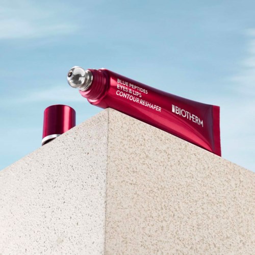 Een rood tube BioTherm huidverzorgingsproduct op de rand van een gebouw met blauwe lucht erboven.