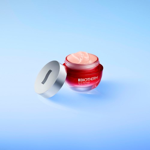 Czerwony pojemnik na krem nawilżający z kremem wewnątrz, oznaczony 'Biotherm' i 'Blue Phenomena.'