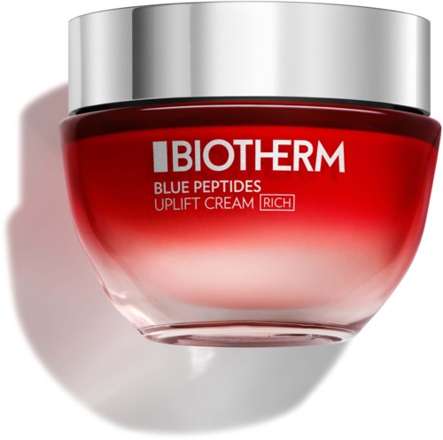 Purnukka BIOTHERM Blue Peptides Uplift Cream, punainen ja hopeinen pakkauksia, varjossa pinnalla.