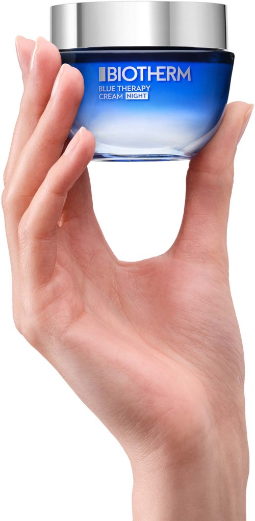 Hand som håller en blå Biotherm hudvårdsburk med silverlock, märkt Blue Therapy Cream Night.