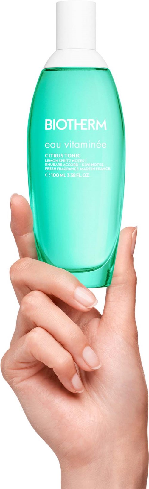 Eine Hand hält eine grüne Flasche mit Biotherm Eau Vitaminée Citrus Toner.