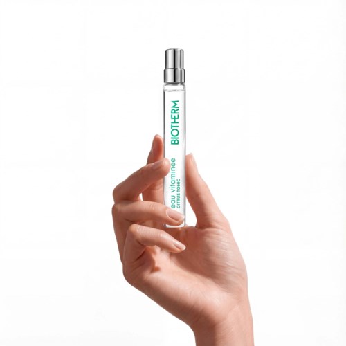 Een hand houdt een kleine doorzichtige tube met zilveren deksel, gemarkeerd BioTherm en met huidverzorgingsserum.