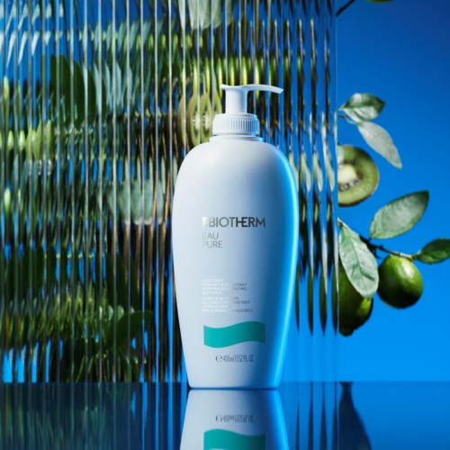 Eine weiße Pumpflasche mit dem Label Biotherm Aqua Pure vor lebendigem Hintergrund mit grünen Blättern und blauen Tönen.