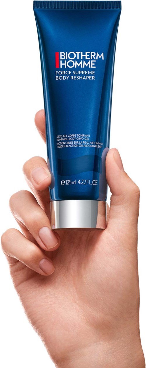 Een hand houdt een blauwe tube van Biotherm Homme Force Supreme Body Reshaper huidverzorgingsproduct.