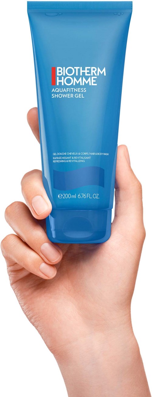 Hånd som holder en blå tube med Biotherm Homme Aquafitness dusjgelle.