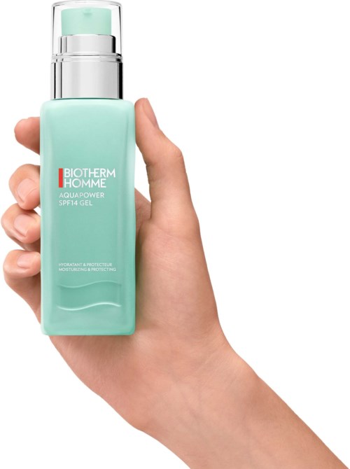 En hånd holder en lys grønn flaske med Biotherm Homme Aqua Power SPF14 gel med sølvpumpedispenser.