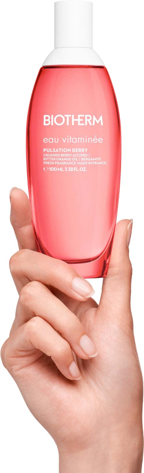 Een hand houdt een roze flacon van Biotherm huidverzorging met witte dop en label.
