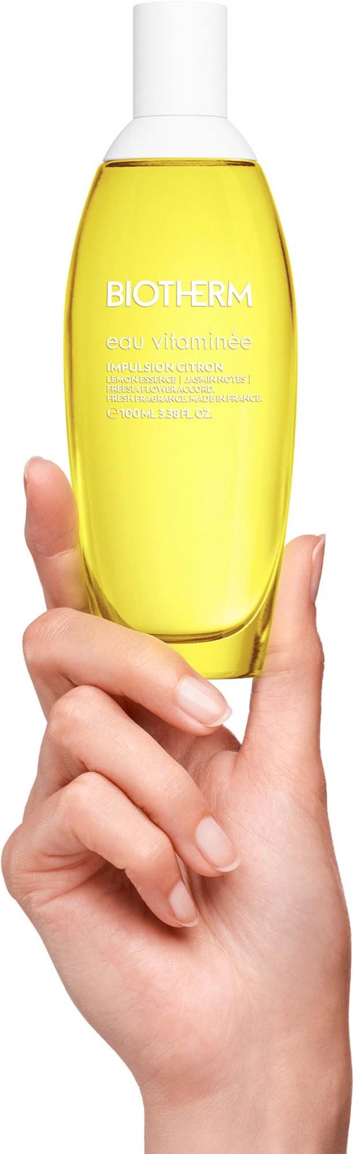 Een hand houdt een gele Biotherm huidverzorgingsfles met witte dop.