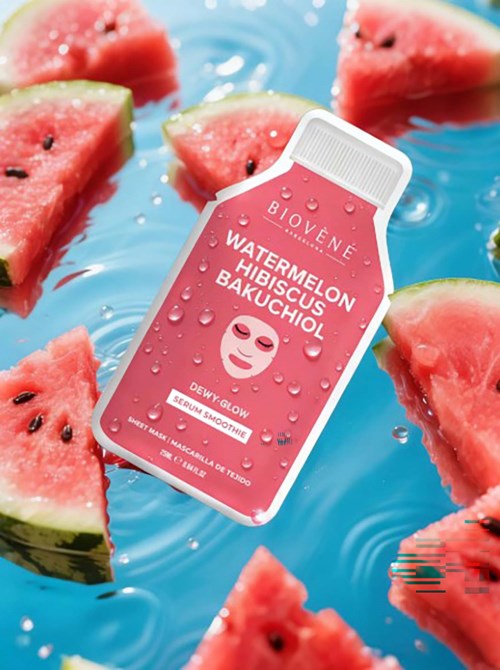 A pink skincare product bottle surrounded by watermelon slices in water, with water droplets on the bottle.