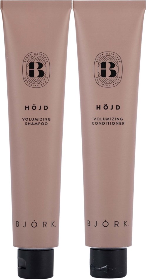 Zwei beige Flaschen, eine für Shampoo und eine für Conditioner, mit schwarzen Texten und Logos, stehen aufrecht.