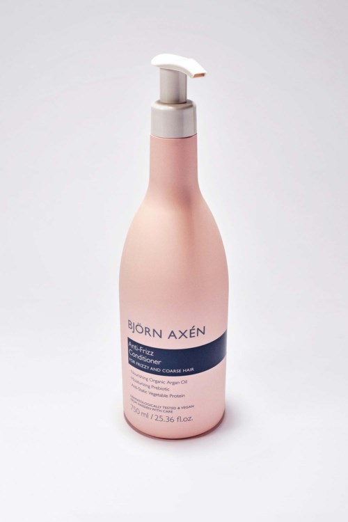 Roze fles met pomp, labeled Björn Axén, voor haarconditioner of shampoo.