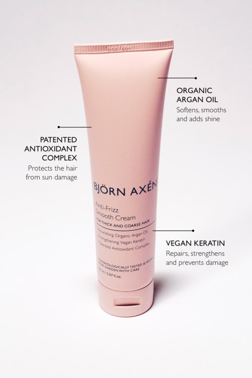 Een roze tube haarcrème met labels die natuurlijke ingrediënten en voordelen voor haargezondheid benadrukken.