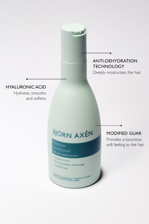 Eine weiße Flasche mit blauer Beschriftung bewirbt Haarconditioner mit Feuchtigkeitsversorgung, Anti-Dehydration-Technologie und luxuriösem weichem Gefühl.