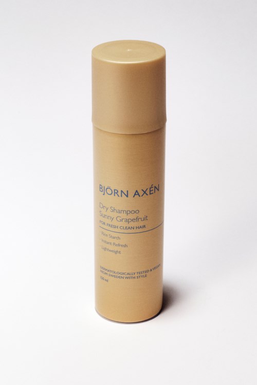 Een beige cilindervormige fles met blauwe tekst, waarschijnlijk shampoo, staand op een witte achtergrond.