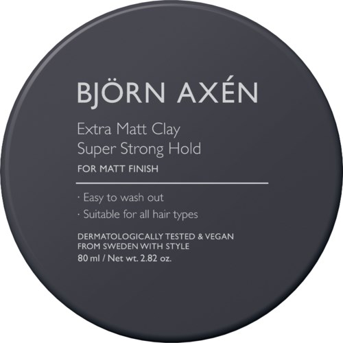 Een donkere ronde sticker met witte tekst die Bjorn Axen haarstylingklei promoot, met nadruk op sterke hold, gemakkelijke wasbaarheid en geschiktheid voor alle haartypes.