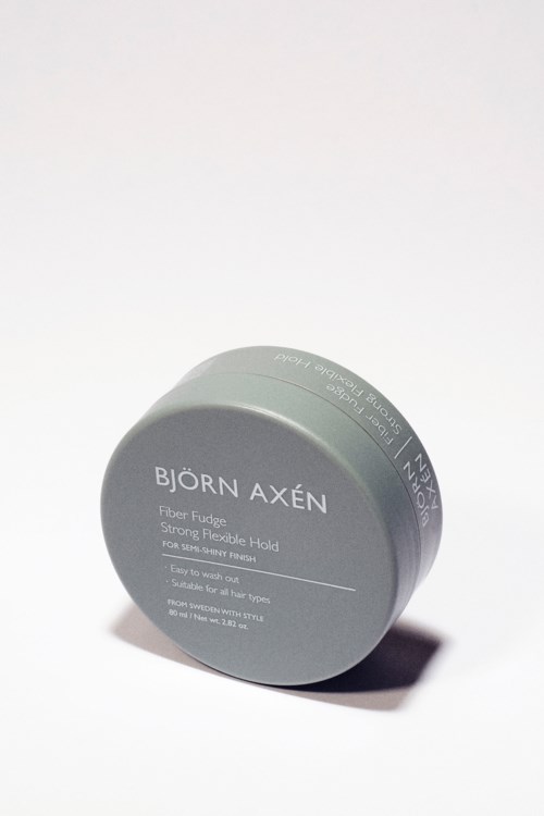 Ein grauer runder Behälter mit schwarzem Text, gekennzeichnet Björn Axén Fiber Fudge für Haarstyling.
