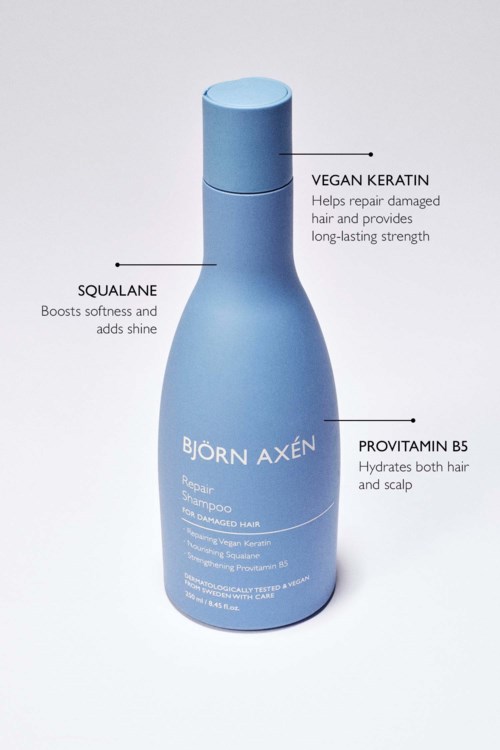 Blauwe shampoo fles met labels voor veganistisch keratine, squalane en provitamine B5.