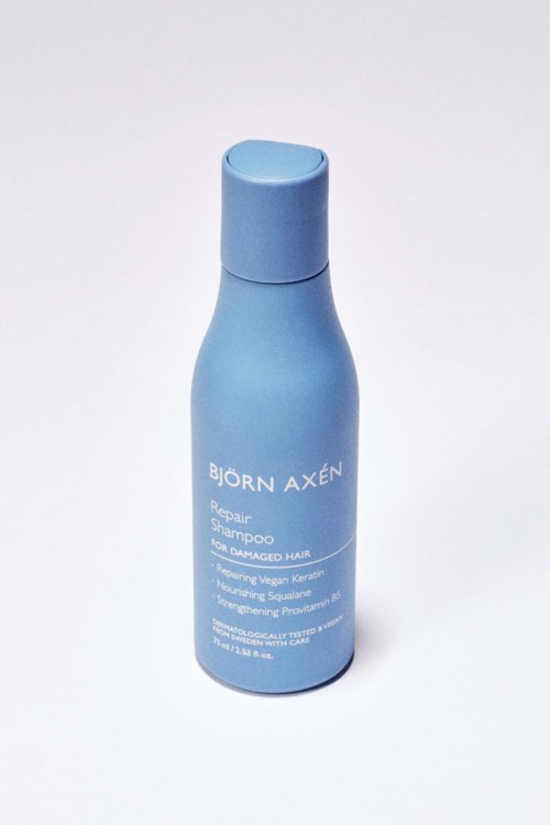 Blauwe fles met 'Björn Axén Repair Shampoo' voor beschadigd haar.