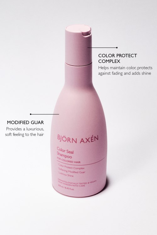 Roze fles met tekst over shampoo, met labels voor kleurbescherming en luxe gevoel.