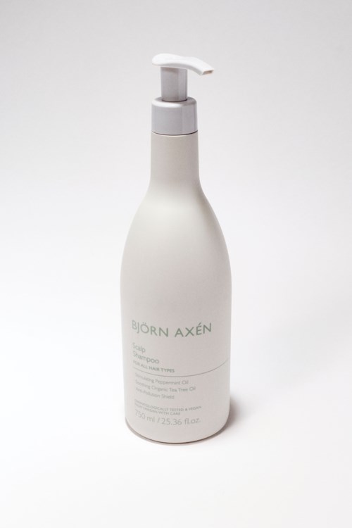 Een witte fles met pomp, gelabeld Björn Axén haarverzorgingsproduct, op een eenvoudige achtergrond.