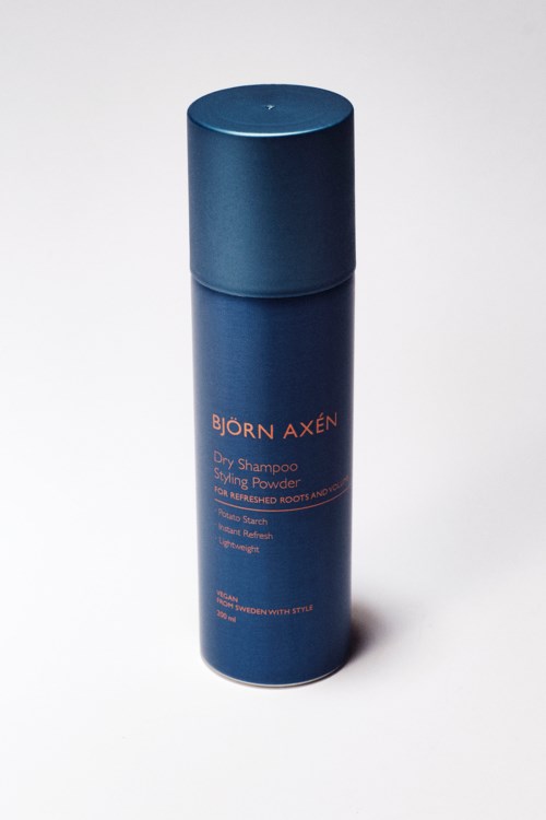 Eine blaue Flasche Björn Axén Trockenshampoo mit orangem Text, steht auf weißem Hintergrund.