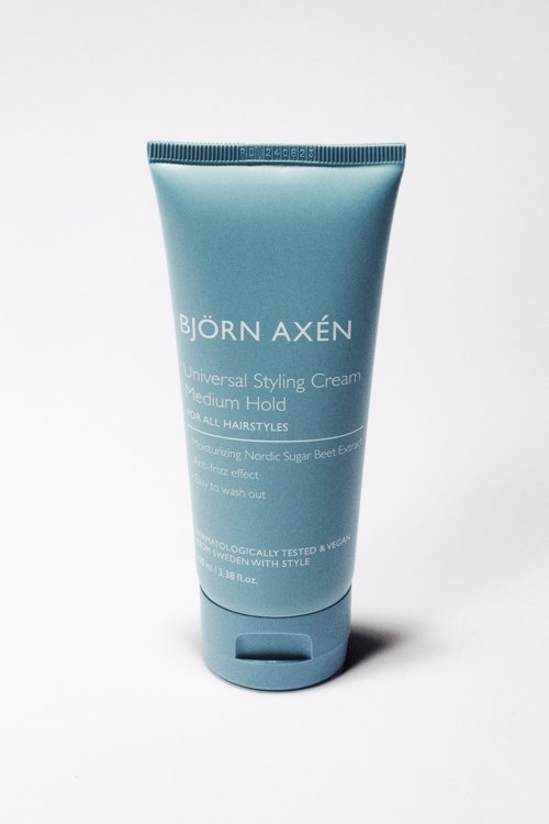 Eine blaue Tube mit Björn Axén Universal Styling Cream in Weißer Schrift, steht auf hellem Hintergrund.