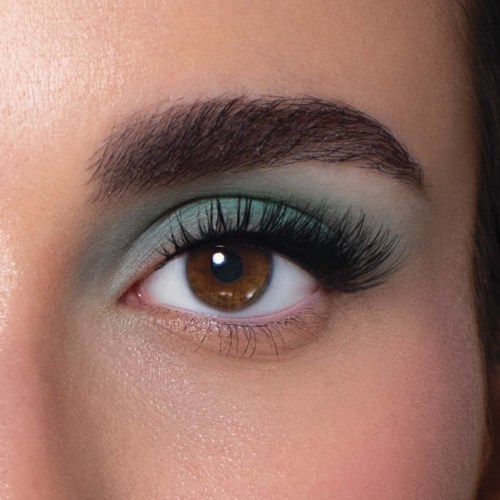 Close-up van een oog met bruin iris, heldere blauwe oogschaduw en lange zwarte wimpers.
