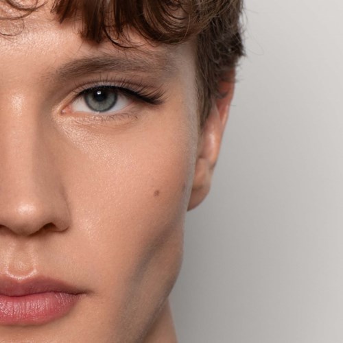 Close-up van iemands gezicht met een blauw oog, deel van de wenkbrauw en wang met gladde huid.