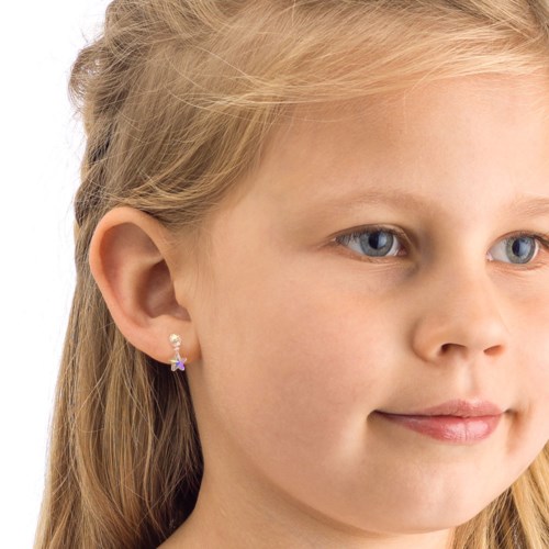 A young girl with blonde hair and blue eyes, wearing a small star-shaped earring, looking calmly to the side.