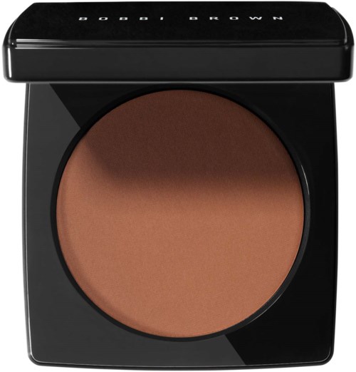 Ett runt makeuppaket med brunt puder inuti och ett svart lock med vit text.