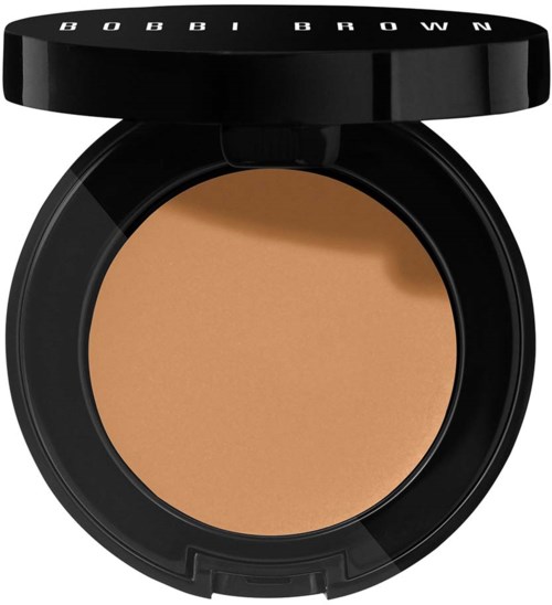 Een ronde make-up compact met beige poeder en een zwart deksel met 'BOBBI BROWN' erop.