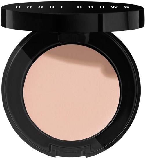 En rund kompakt med svart lock med texten 'BOBBI BROWN' innehåller ljusbeige puder.