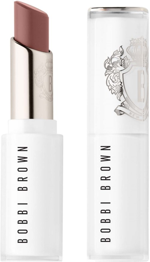 A lipstick in white packaging with a silver cap, showing a light pink color. The lipstick tube has "BOBBI BROWN" written on it.